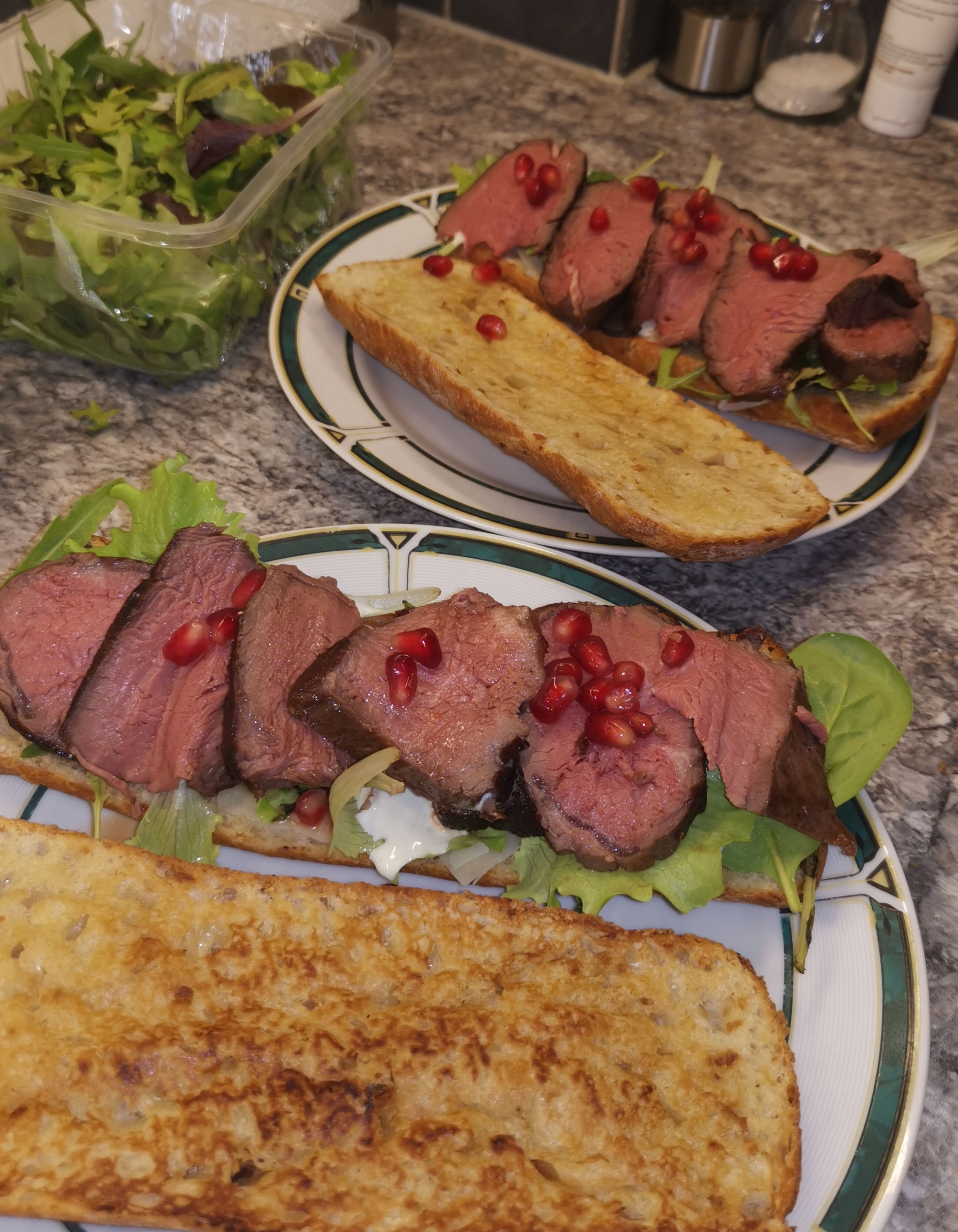 Filetsteak auf Zwiebelbaguette mit Caesar Salad und Granatapfelkernen