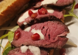 Filetsteak auf Zwiebelbaguette mit Caesar Salad und Granatapfelkernen