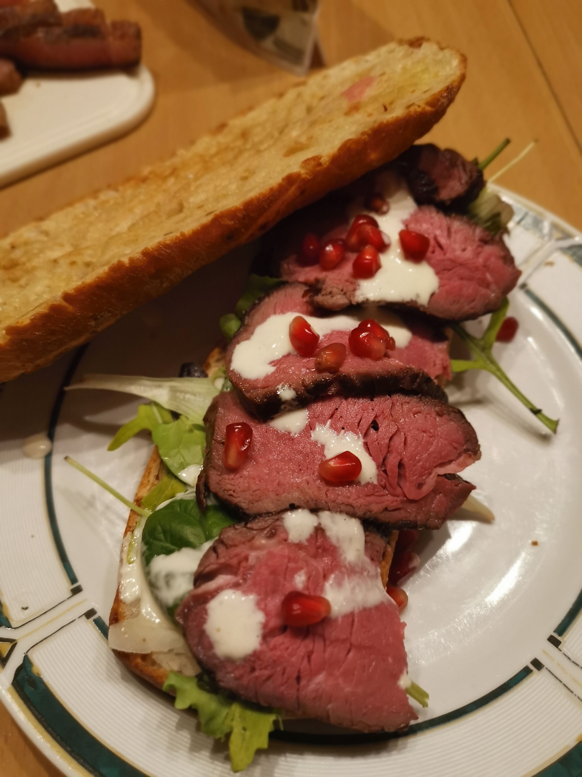 Filetsteak auf Zwiebelbaguette mit Caesar Salad und Granatapfelkernen